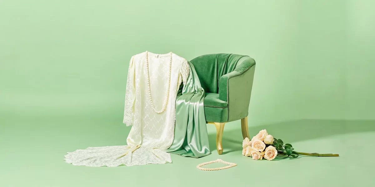 A boudoir wardrobe guide with a lace robe, pearls, and roses on a green velvet chair.