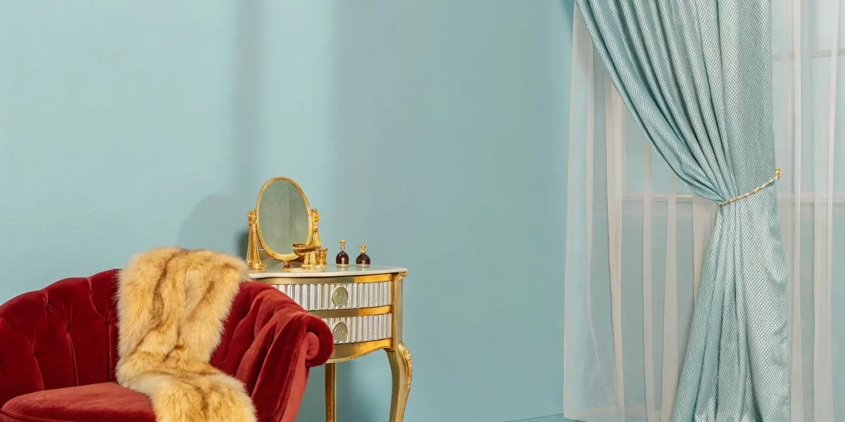 A glamorous old Hollywood boudoir scene with a red velvet chair and vintage gold vanity.