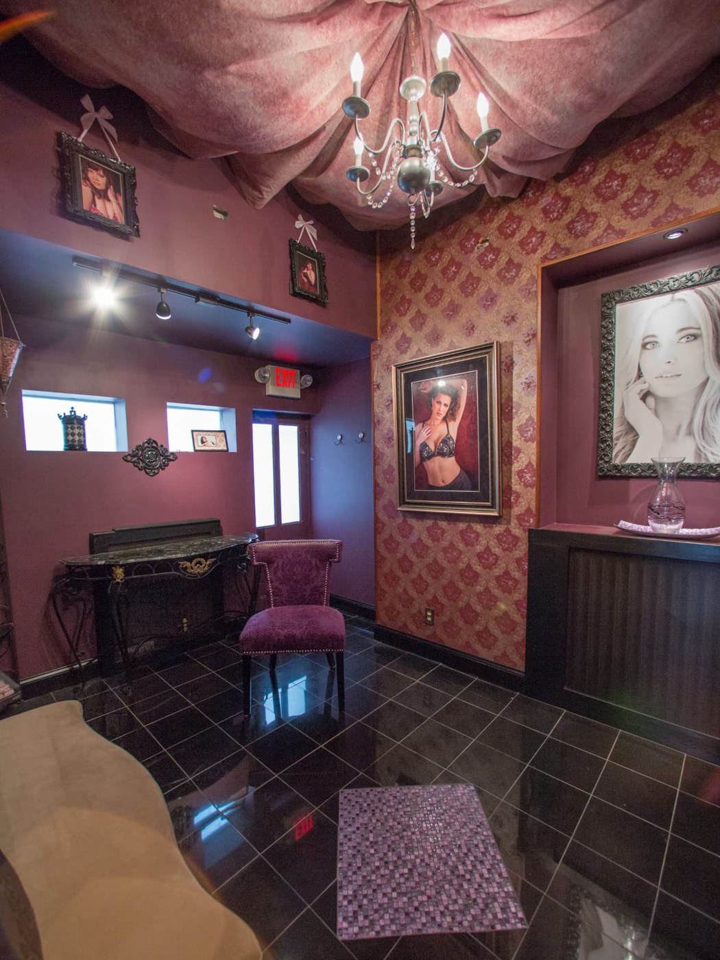 The studio lounge, with a draped fabric ceiling gathered around a chandelier, plum walls and damask wallpaper