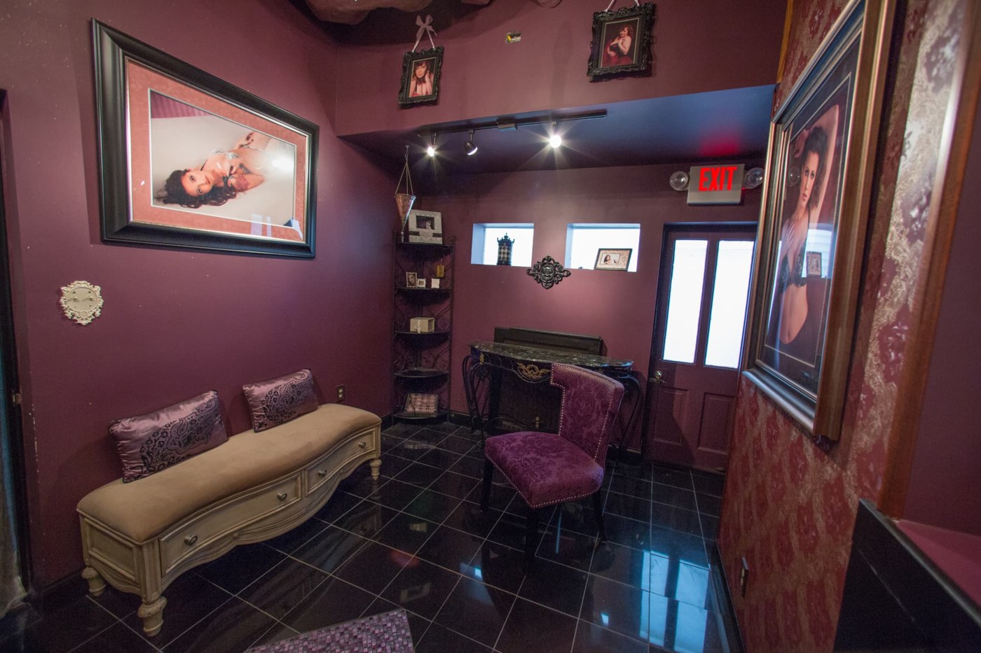 The studio lounge seating area, with a tufted bench, framed portrait and corner display shelf