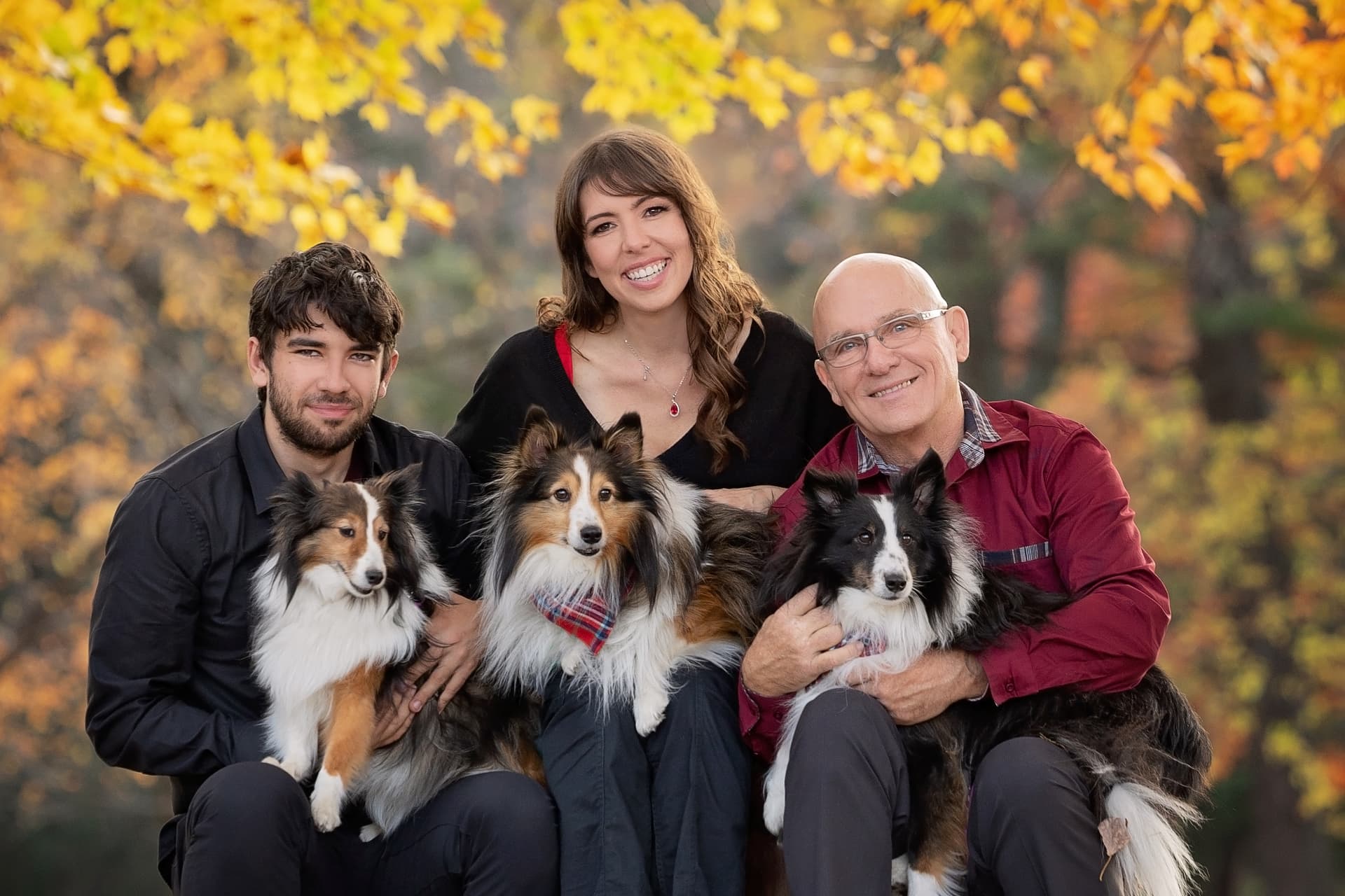 Jeff and Rachel Owen with family and their three shelties in front of autumn leaves